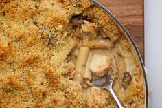 a casserole dish filled with pasta and meat covered in gravy on top of a wooden table