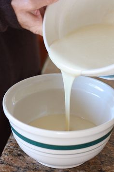 a person pouring milk into a white bowl