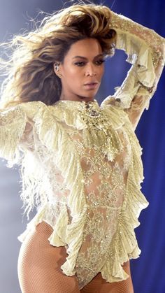 a woman in tights and heels on stage with her arms behind her head, looking at the camera