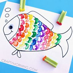 a colorful fish made out of colored crayons on top of a sheet of paper