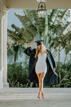 a woman wearing a graduation cap and gown walks down the street in front of palm trees