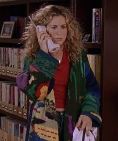 a woman talking on a cell phone in front of a bookcase