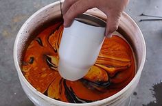 a person pouring orange liquid into a bucket