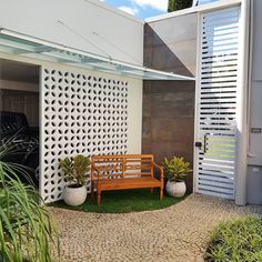 a wooden bench sitting in the middle of a garden next to a white wall and door