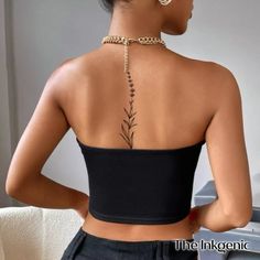 the back of a woman's top with a plant tattoo on her left shoulder