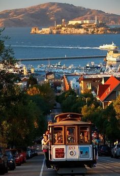 a cable car traveling down a street next to the ocean