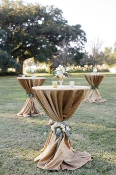 an outdoor setting with tables and chairs covered in burlock, flowers and greenery