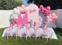 a table set up for a barbie birthday party with pink and white balloons on the wall