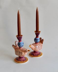 two candles are sitting next to each other with birds on them and one candle is in the shape of a bird