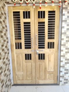 two wooden doors in front of a brick wall with decorative decorations on the top and bottom