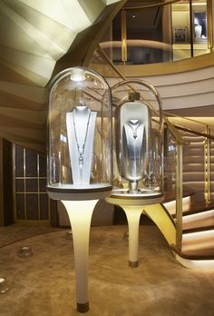 the inside of a glass case with jewelry on display in front of a spiral staircase