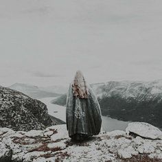 a person standing on top of a snow covered mountain next to a body of water