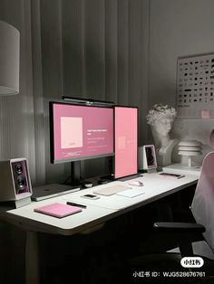 two computer monitors sitting on top of a desk in front of a vase with flowers