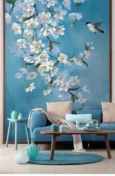 a living room with a blue couch and white flowers on the wall above it is a coffee table