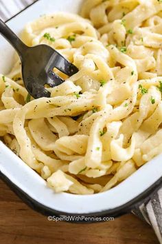 a fork in a bowl of pasta with parsley