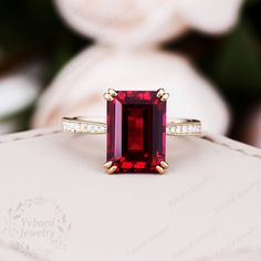 a close up of a ring with a red stone in the middle and diamonds around it