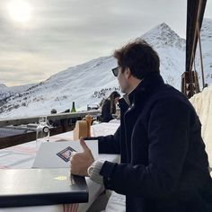 a man sitting at a table in front of a mountain