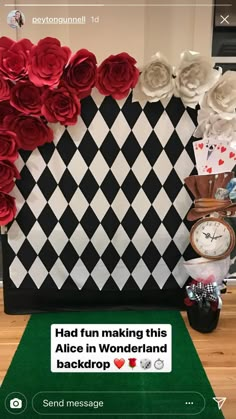 a black and white checkerboard wall with red roses on it, next to a clock