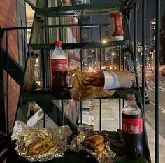 some food is sitting on top of a metal rack near a building and street at night