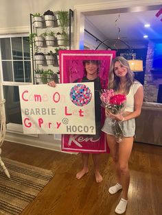 two young women holding flowers and a sign