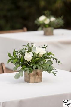 there is a vase with white flowers on the table in front of two empty tables