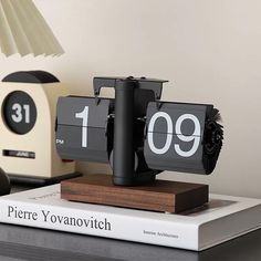 a clock sitting on top of a table next to a lamp and bookends