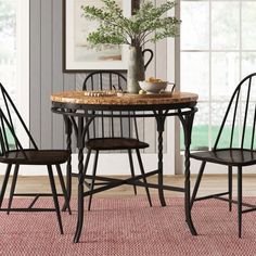 a dining room table with chairs and a vase on top of it in front of a window