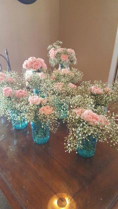 several vases filled with baby's breath flowers on top of a wooden table