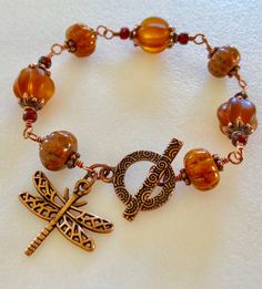 a bracelet with beads, charms and a dragonfly on it's clasps