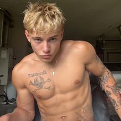 a shirtless young man with tattoos on his chest