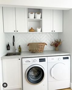 a washer and dryer in a small room with white cabinets on the wall