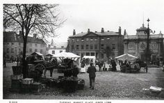 an old black and white photo of people walking around in the street with tents set up