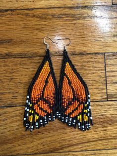 a pair of beaded earrings with an orange and black butterfly design on the front