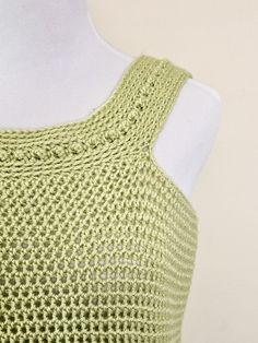 a white mannequin wearing a green knitted top