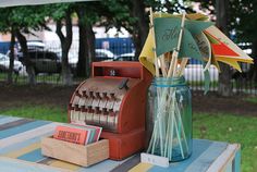 an old fashioned cash register sitting on top of a blue and yellow striped table cloth