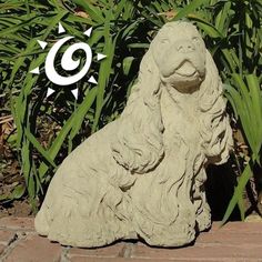 a statue of a dog sitting in front of some plants and grass with the sun above it