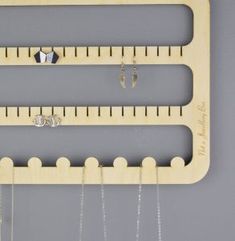 a wooden ruler with earrings hanging from it's sides and two pairs of earrings on each side