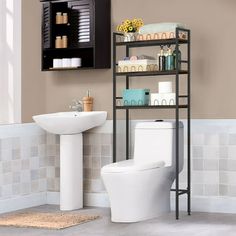 a white toilet sitting next to a bathroom sink under a shelf filled with soaps