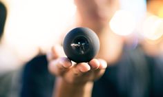 a person holding up a black object in their hand with blurry lights behind them