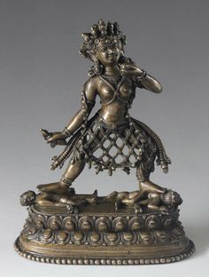 a bronze statue with an elaborate design on it's body and arms, standing in front of a gray background