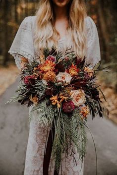 a woman in white dress holding a bouquet with orange and red flowers on it's side