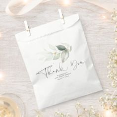 a thank bag with the words thank you on it next to some baby's breath flowers