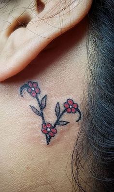 a woman's neck with a flower tattoo on her left side behind the ear