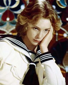 a young woman wearing a sailor's uniform and holding her hand to her face