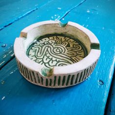 a blue wooden table topped with a bowl filled with water and an intricate design on it