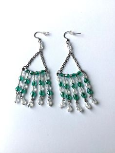 green and white beaded chandelier earrings on a white surface with silver chains