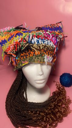 a mannequin head wearing a multicolored hat with beads on it and a ball of yarn