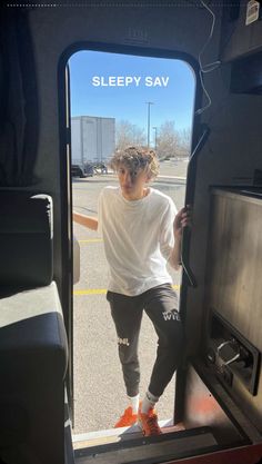 a young man standing in the doorway of a vehicle