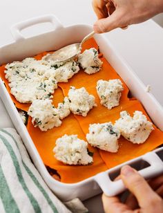 a person scooping cheese into a casserole dish