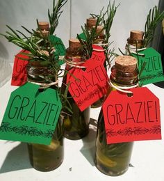 four small bottles with labels on them are sitting on a table, one is empty and the other has grass in it